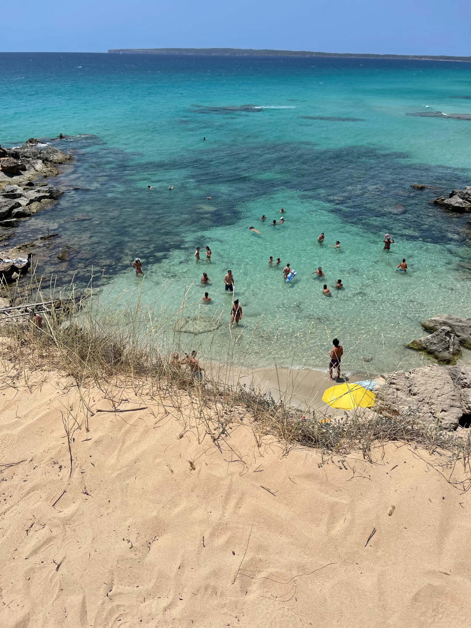 Vue plongeante sur l'eau turquoise et les baigneurs du Caló des Mort à Formentera
