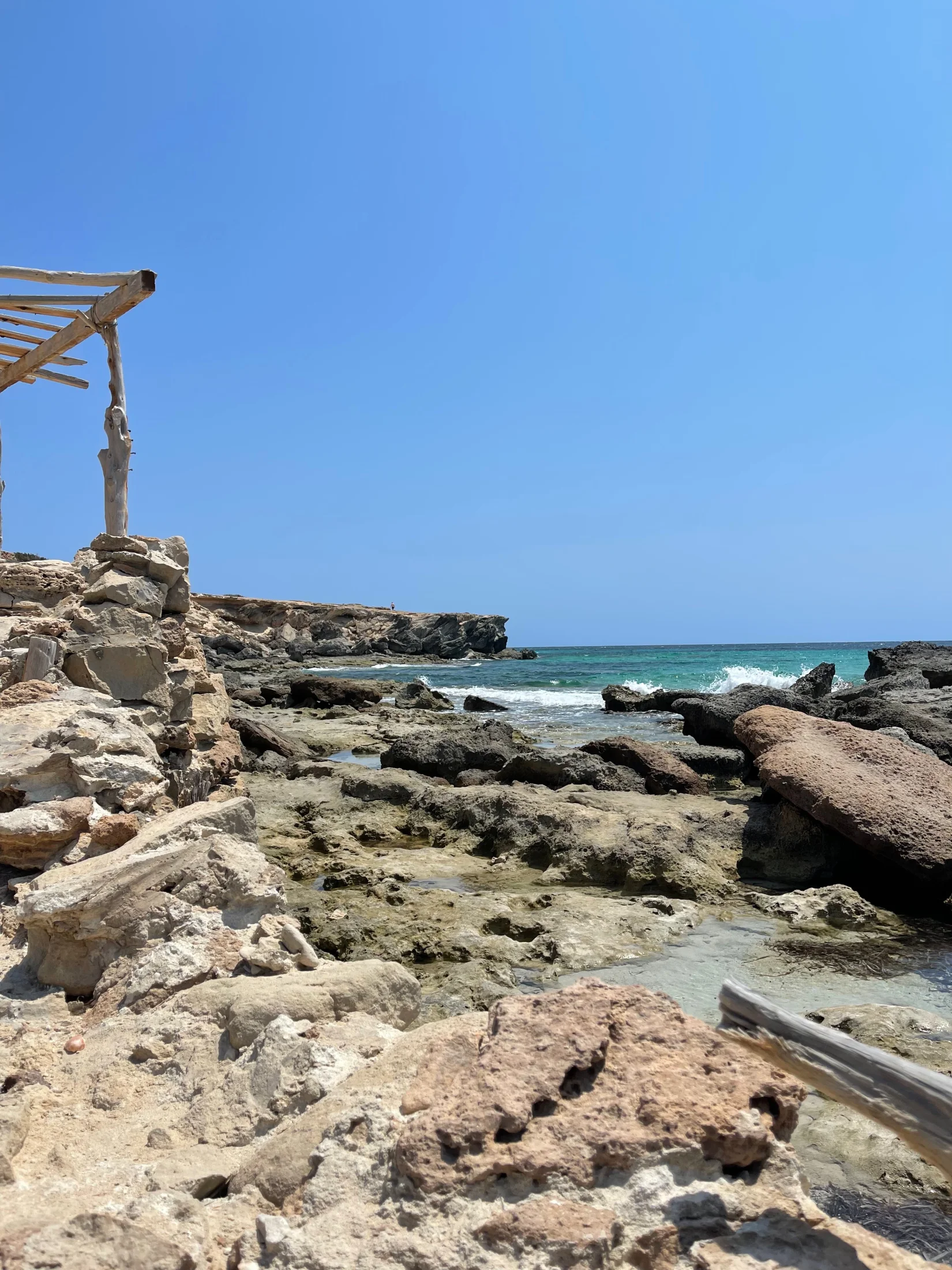 Rochers de grès et abri en bois au bord de l'eau turquoise du Caló des Mort, Formentera