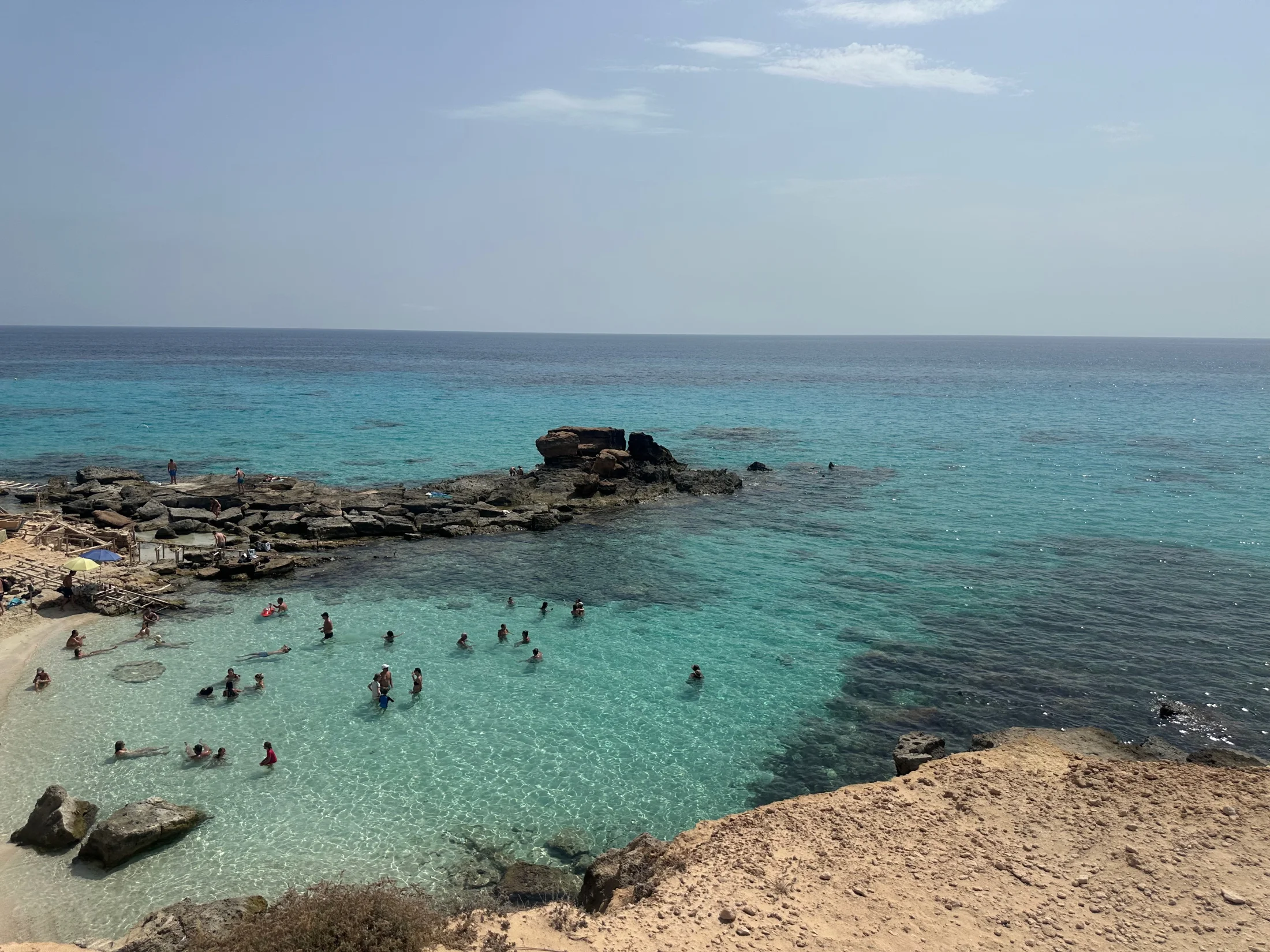 Lagon turquoise et pointe rocheuse du Caló des Mort avec baigneurs, Formentera
