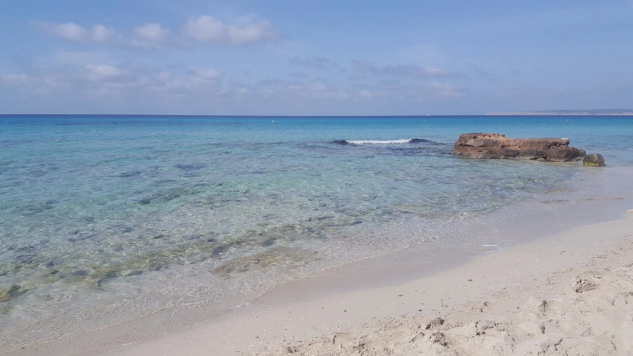 Eau peu profonde et bloc rocheux émergeant sur la plage d'Es Arenals à Formentera