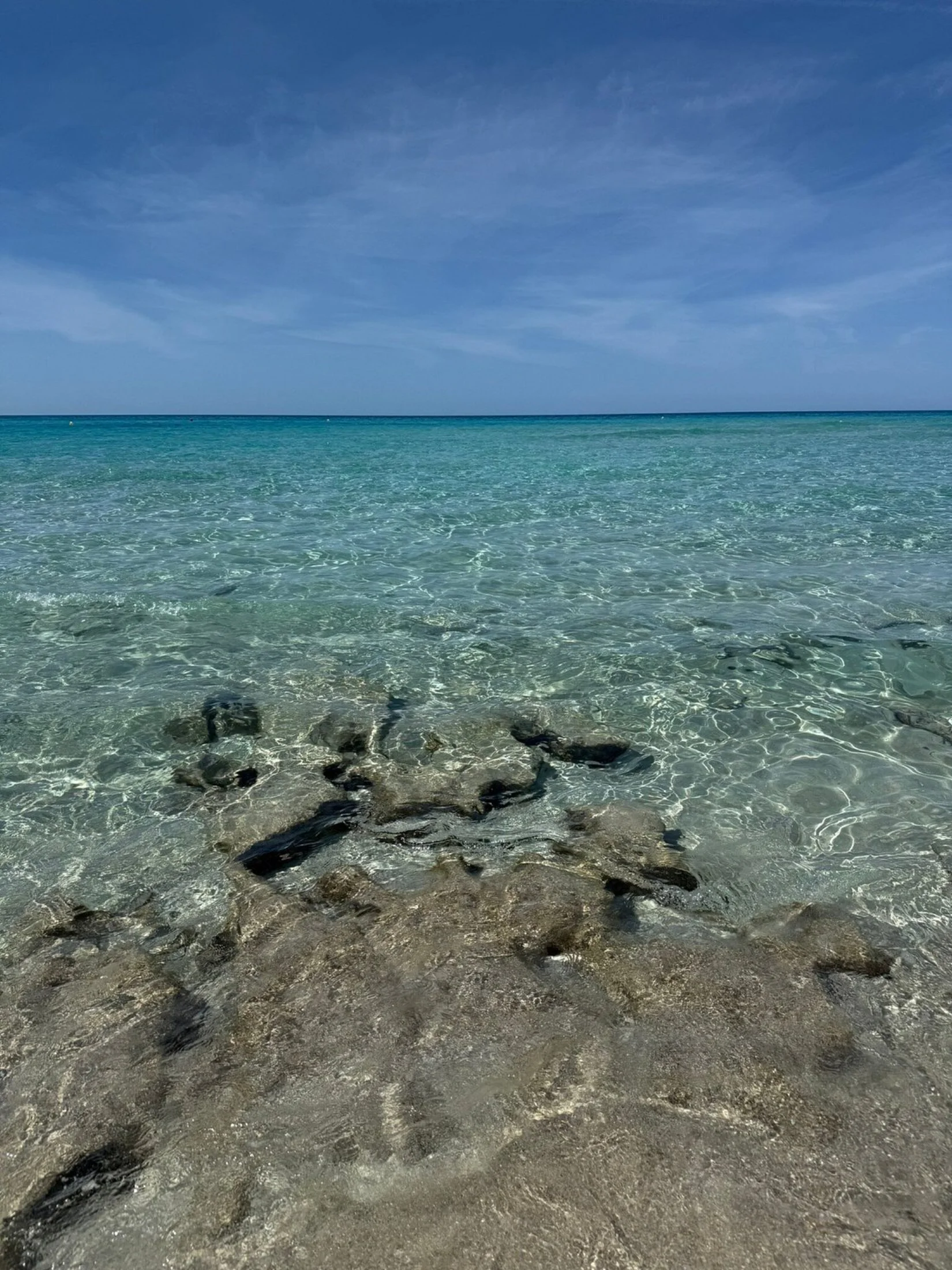 Eau turquoise transparente et fonds rocheux au bord de la plage d'Es Arenals à Formentera