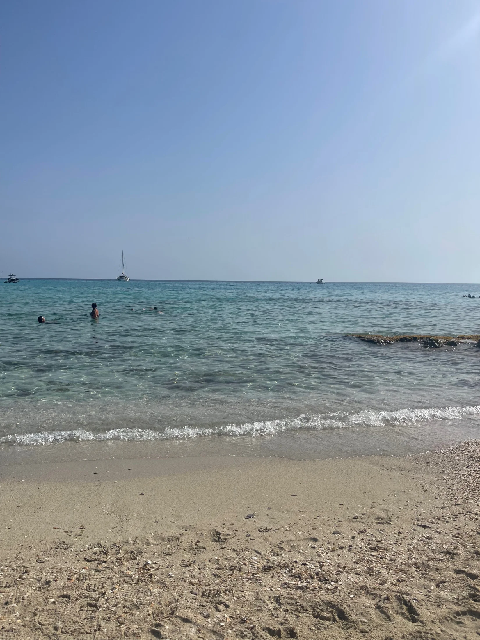 Eau turquoise transparente et baigneurs sur la plage d'Es Arenals à Formentera