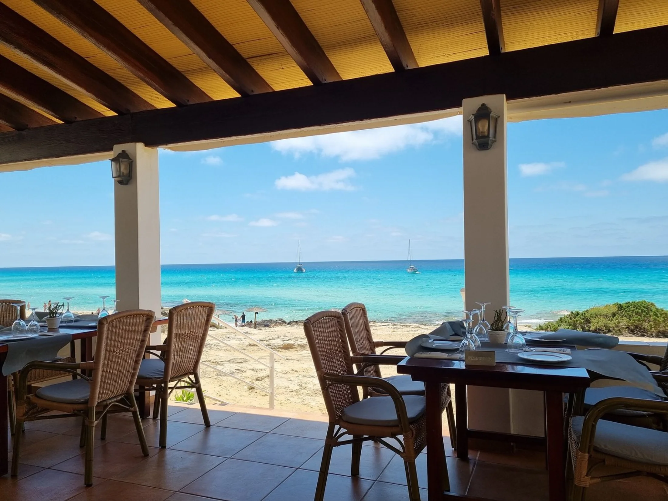 Terrasse d'un restaurant de plage face à la mer turquoise d'Es Arenals, Formentera