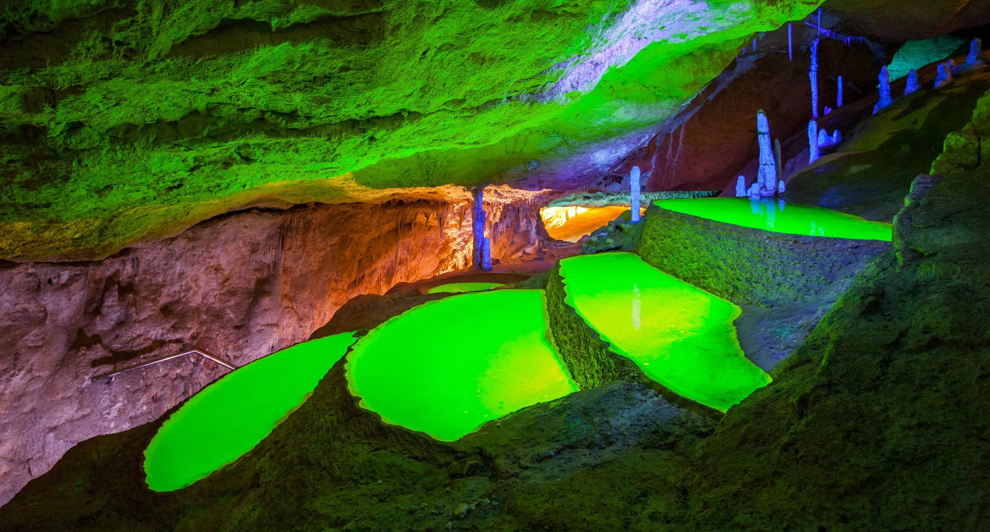 Bassin illuminé en vert par lumière UV dans la grotte de Can Marçà