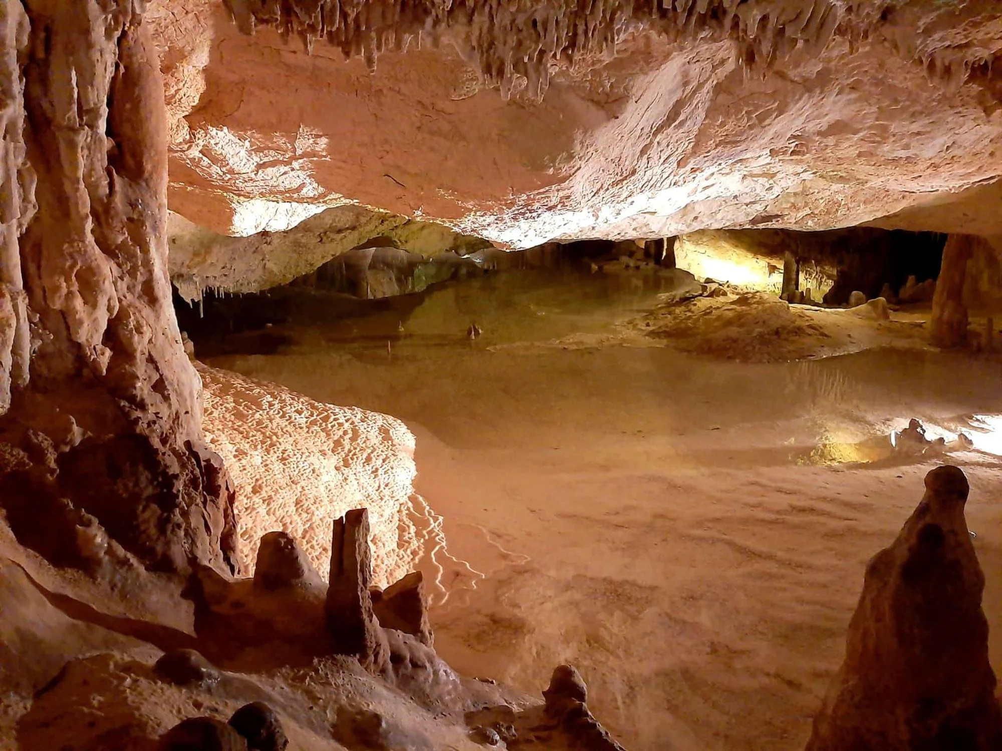 Galerie éclairée de la grotte de Can Marçà avec vue sur le bassin