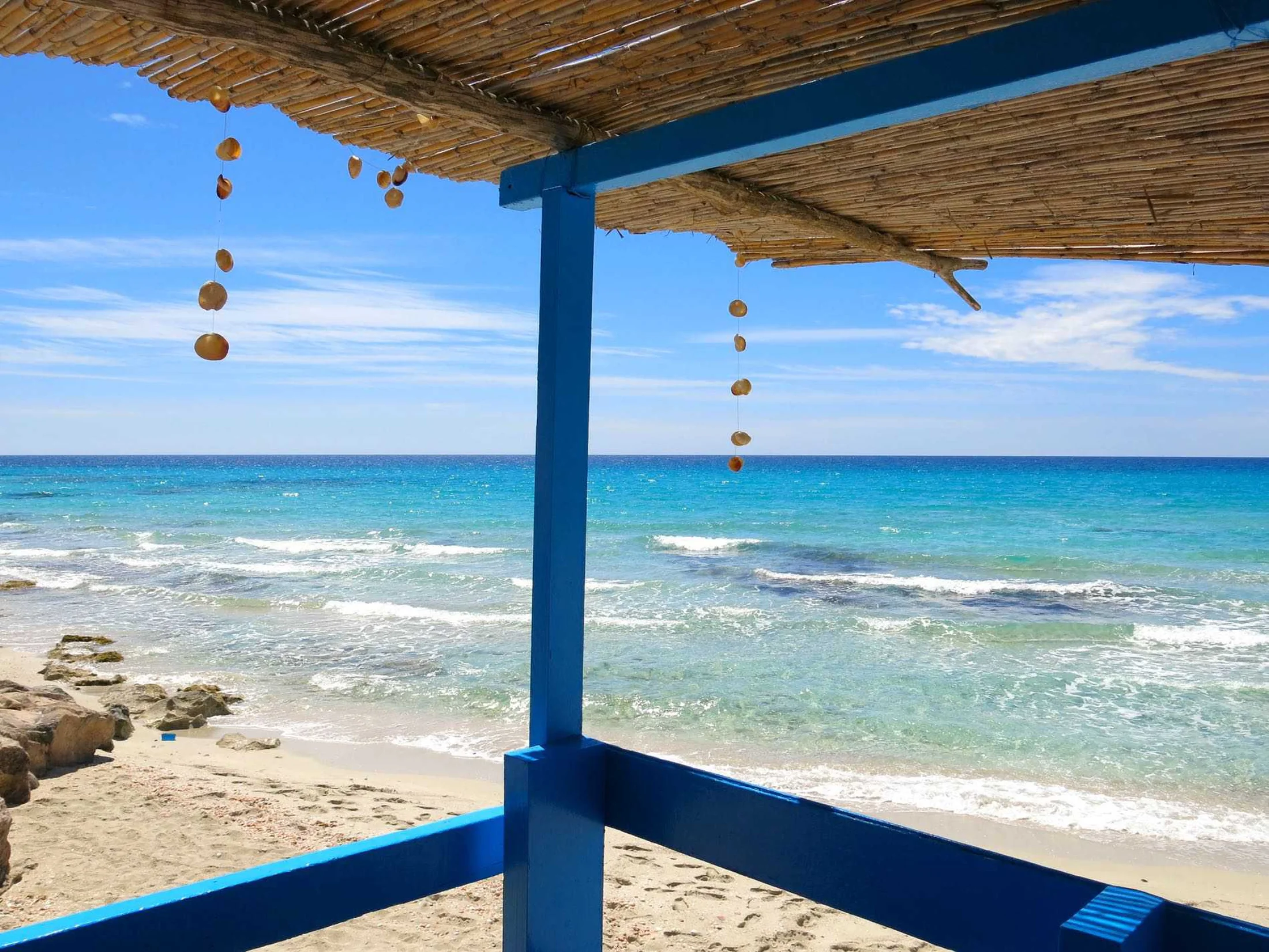 Terrasse ombragée d'un chiringuito bleu face à la mer de Migjorn, Formentera