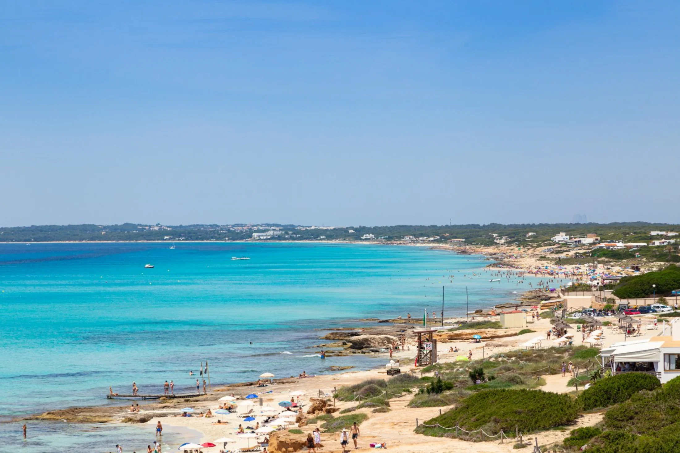 Panorama de la longue plage de Migjorn à Formentera avec parasols et mer turquoise