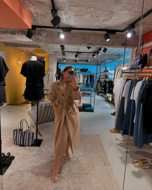 Intérieur de la boutique Mayurka à Ibiza avec cliente essayant un manteau
