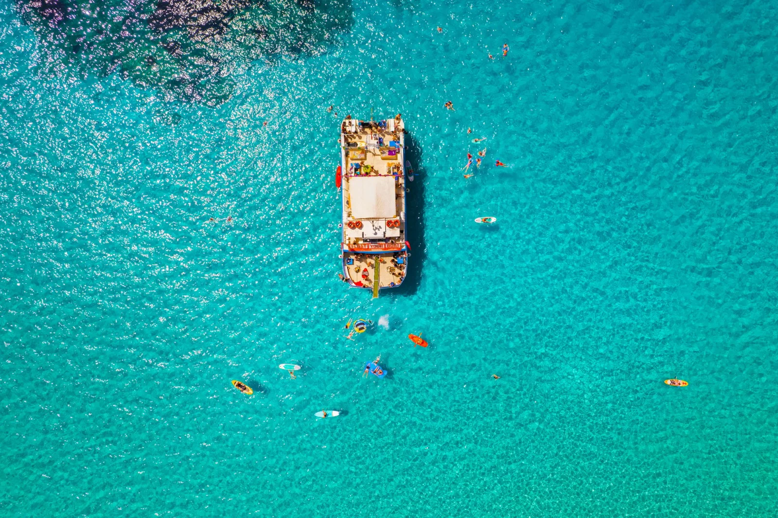Bateau de croisière au mouillage dans l'eau turquoise, baigneurs autour