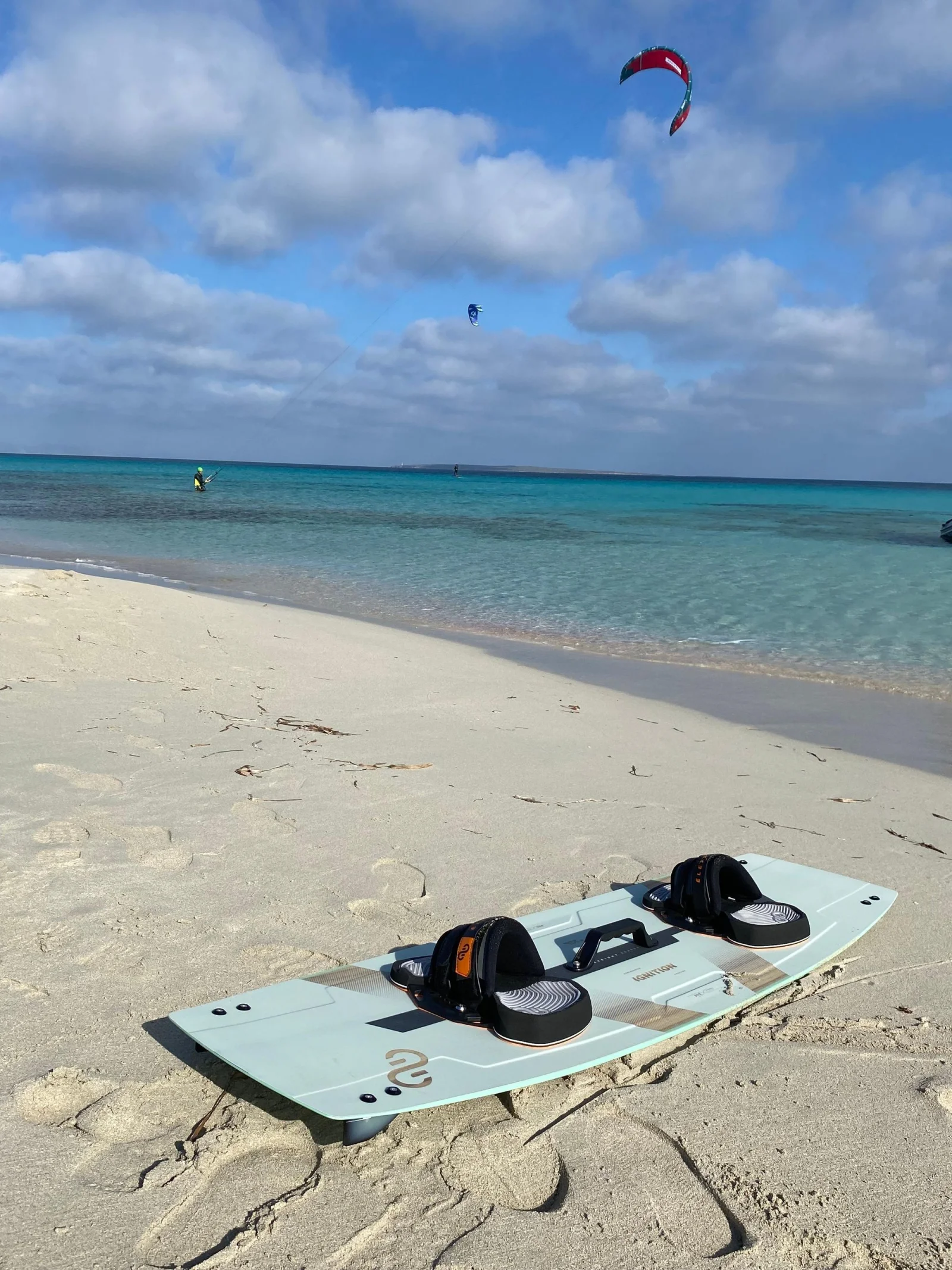 kitesurf formentera planche Planche de kitesurf posée sur le sable, kites dans le ciel