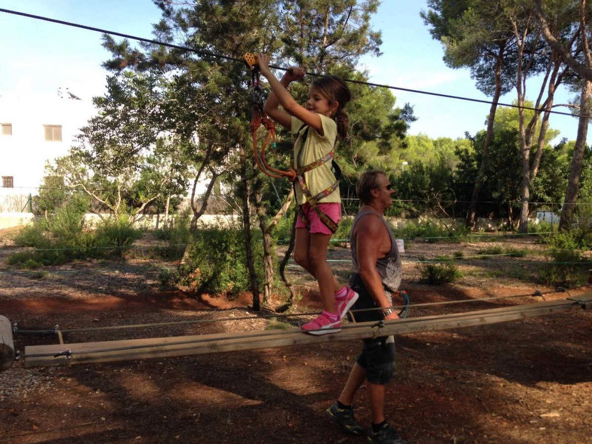 acrobosc ibiza enfant poutre adulte Enfant sur une poutre suspendue du parcours Acrobosc, accompagnée d'un adulte au sol