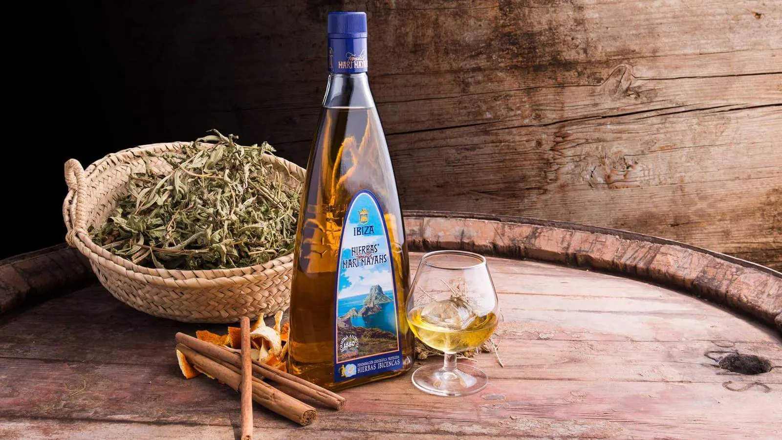 Bouteille de hierbas ibicencas, herbes séchées et verre sur un tonneau