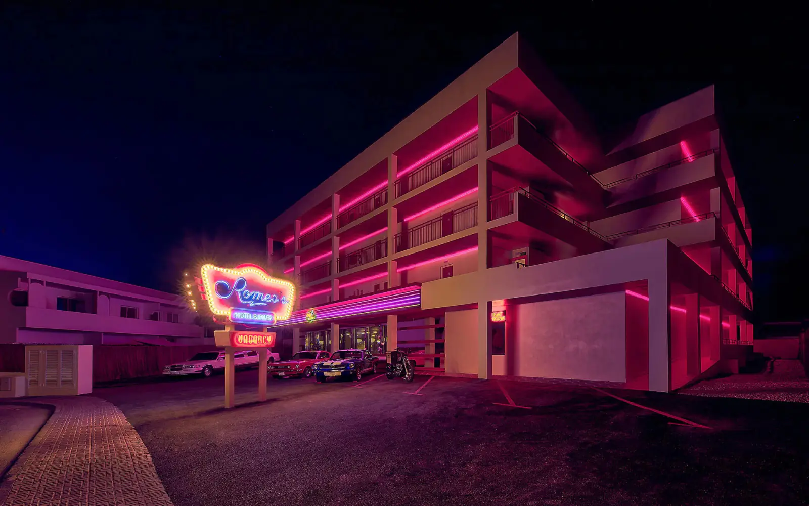 hotel romeo ibiza Façade éclairée au néon rose de l'hôtel Romeo's la nuit