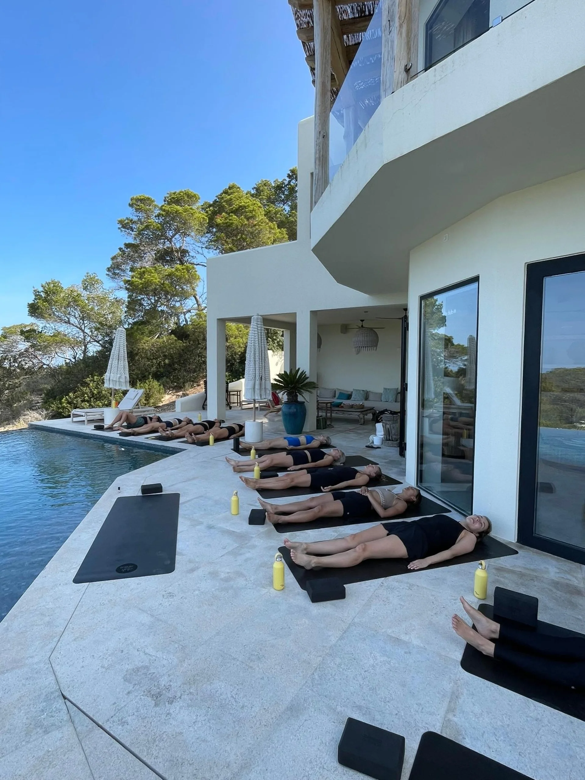 relaxation guidee terrasse villa ibiza Participants allongés sur leurs tapis pour une relaxation guidée sur la terrasse d'une villa d'Ibiza
