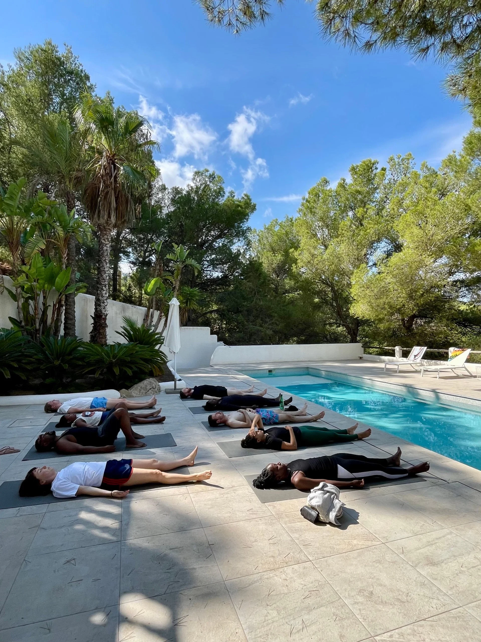 seance yoga piscine retraite ibiza Groupe en relaxation sur des tapis de yoga au bord de la piscine d'une finca d'Ibiza